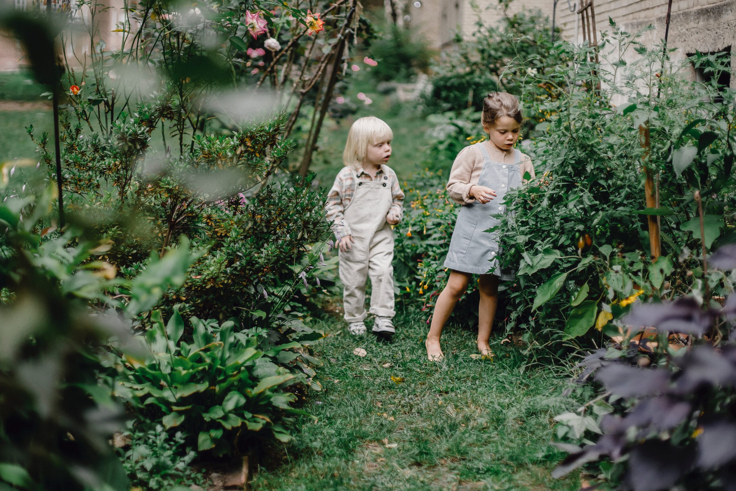 Dwie małe dziewczynki w ogrodzie pełnym kwiatów